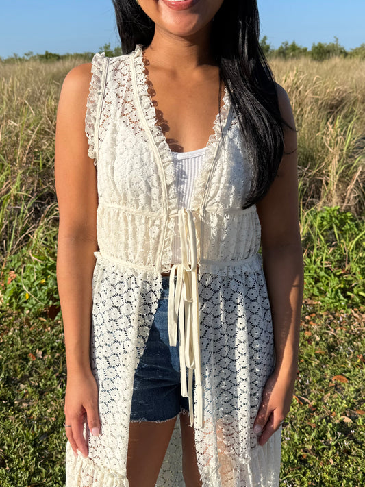 Woman wearing a white lace cover-up in a grassy outdoor setting