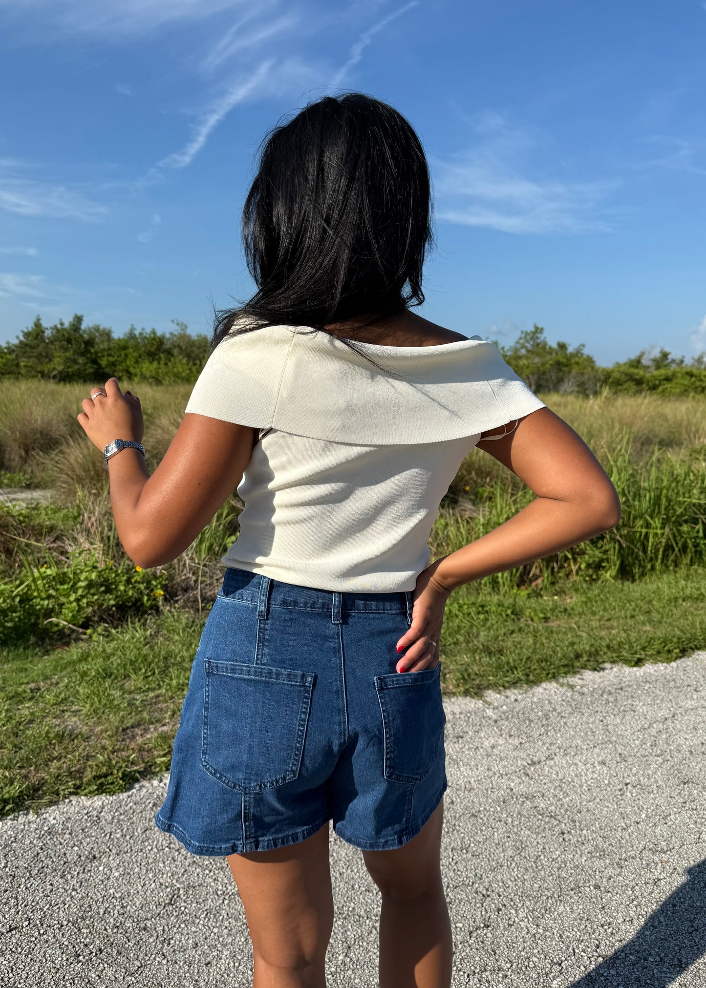 woman wearing denim shorts and a white top on a grass background