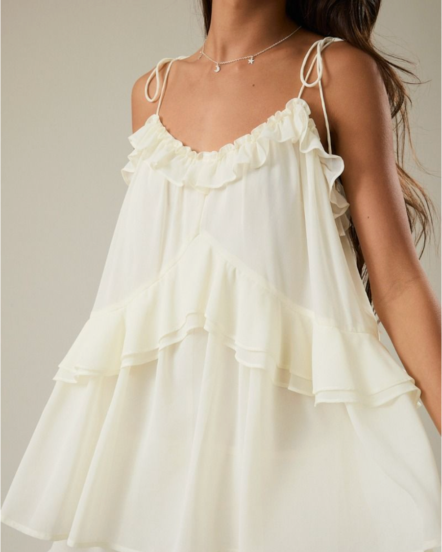 White ruffled dress worn by a person on a neutral background