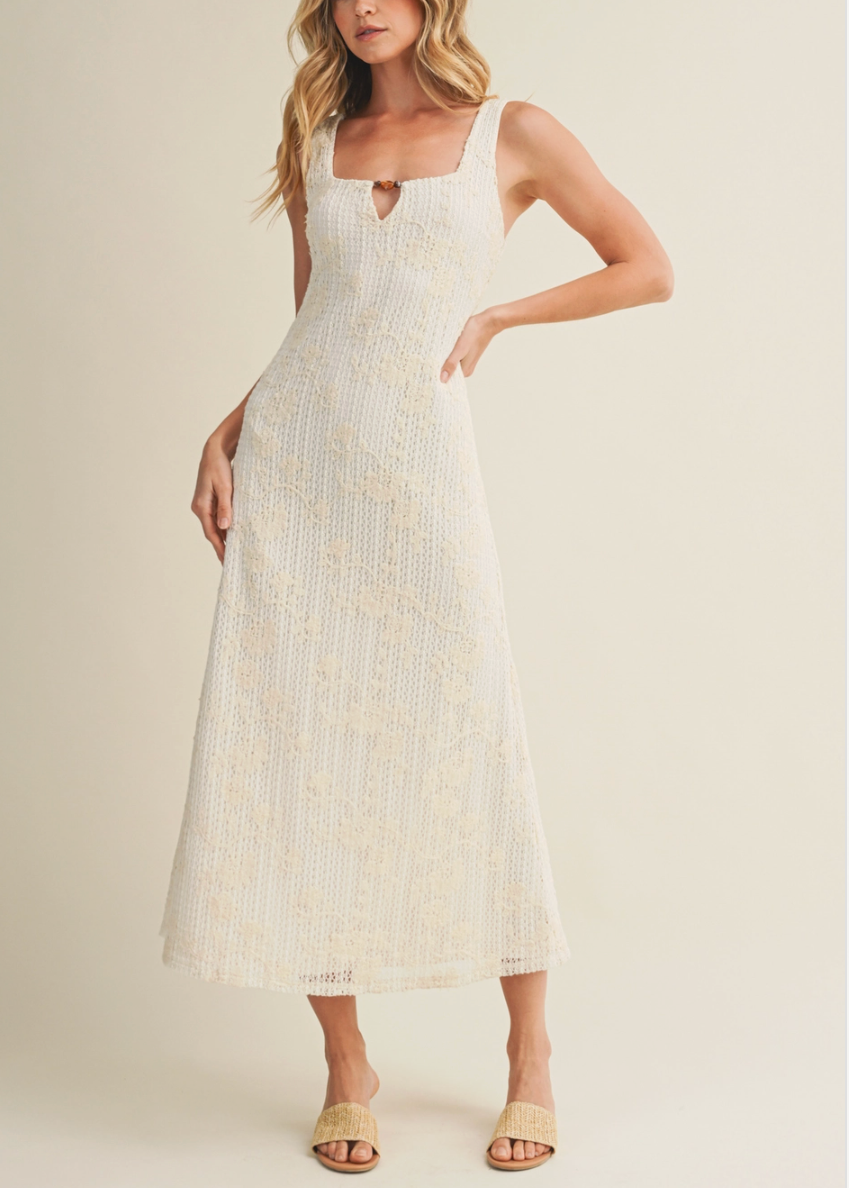 Woman wearing a white dress with a subtle pattern on a plain background