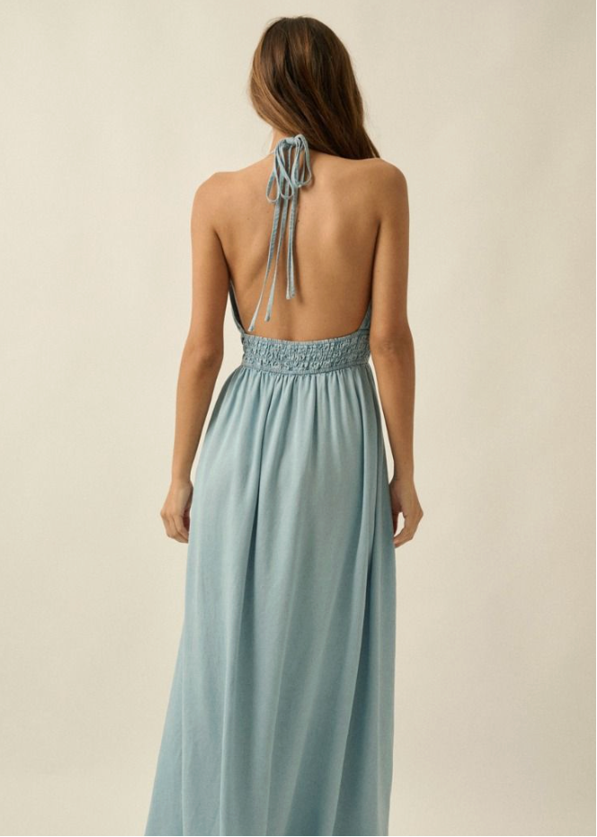 Woman wearing a light blue dress with an open back on a beige background