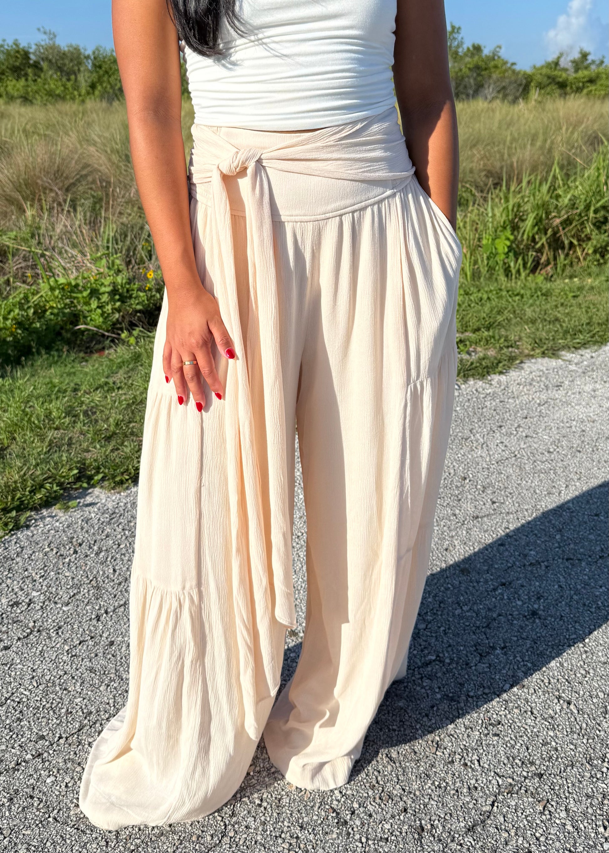 Woman wearing a white tank and shell colored pants on a grass background