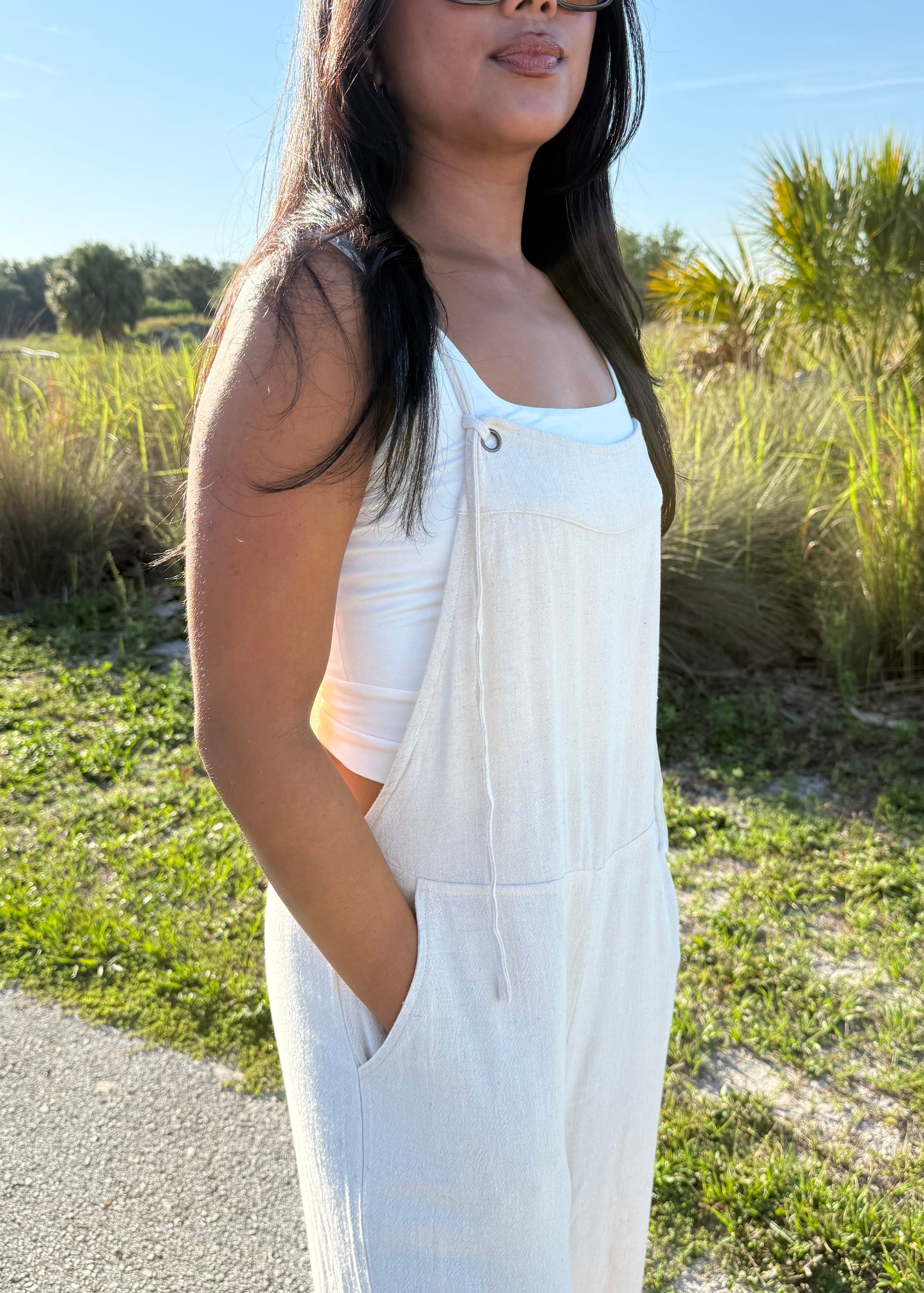 woman wearing a natural colored linen jumpsuit on a grass background