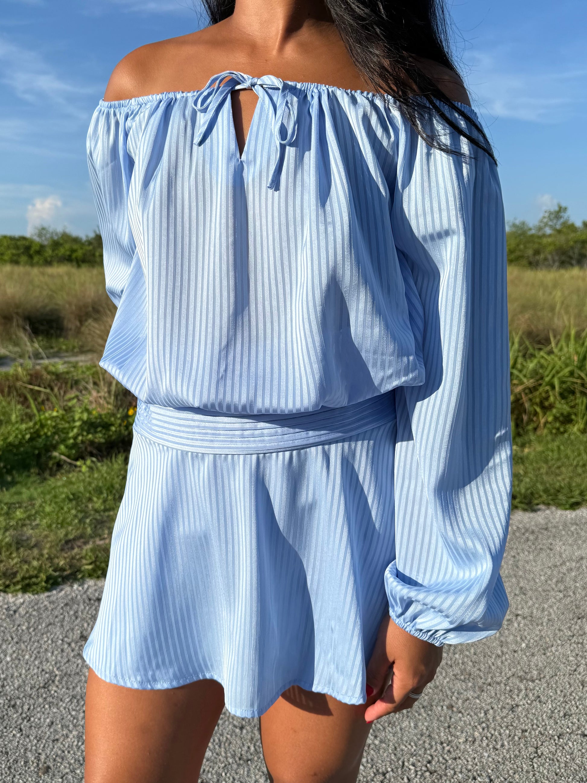 Girl wearing a blue off the shoulder long sleeve romper on a grass background