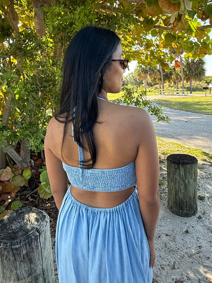 Woman in a blue dress standing outdoors near trees and a path