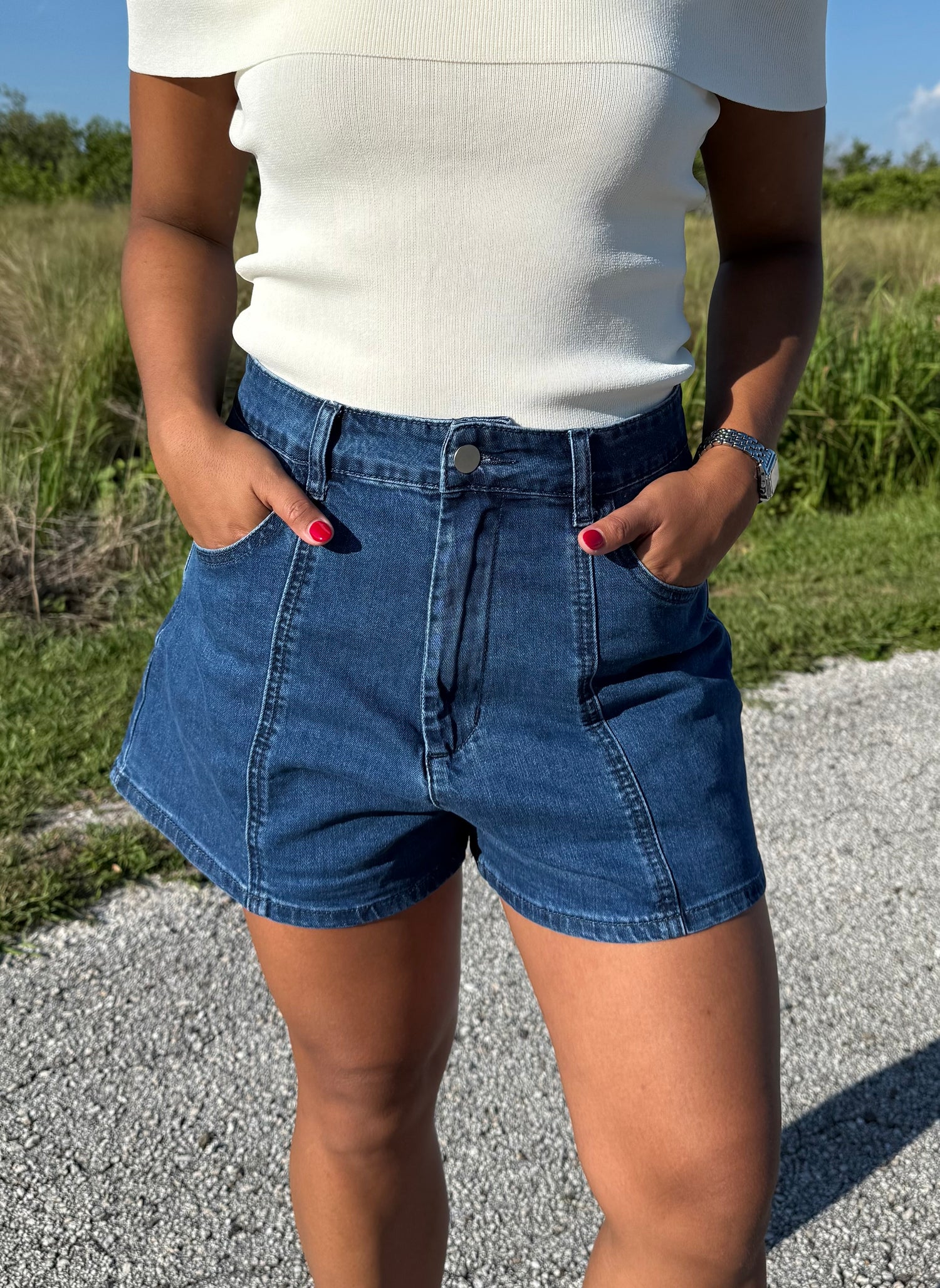 woman wearing denim shorts and a white top on a grass background