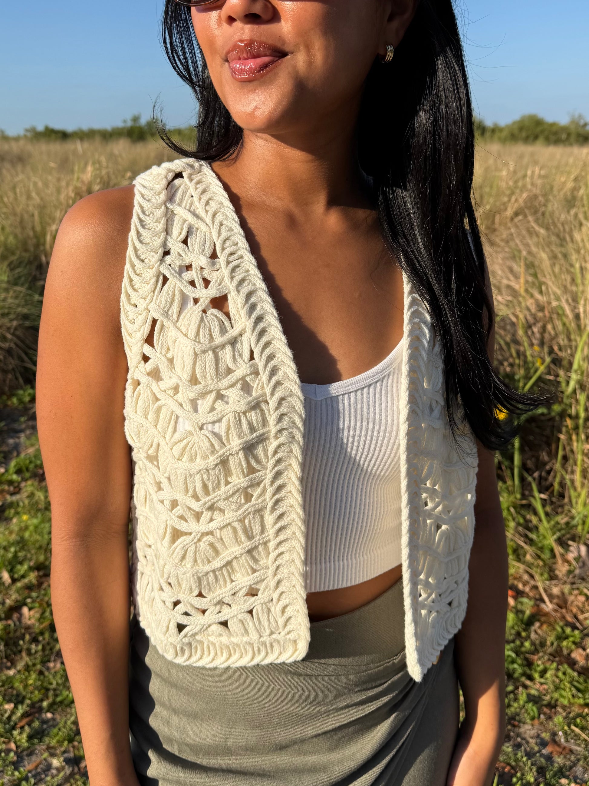 Woman wearing a white crochet vest in a field