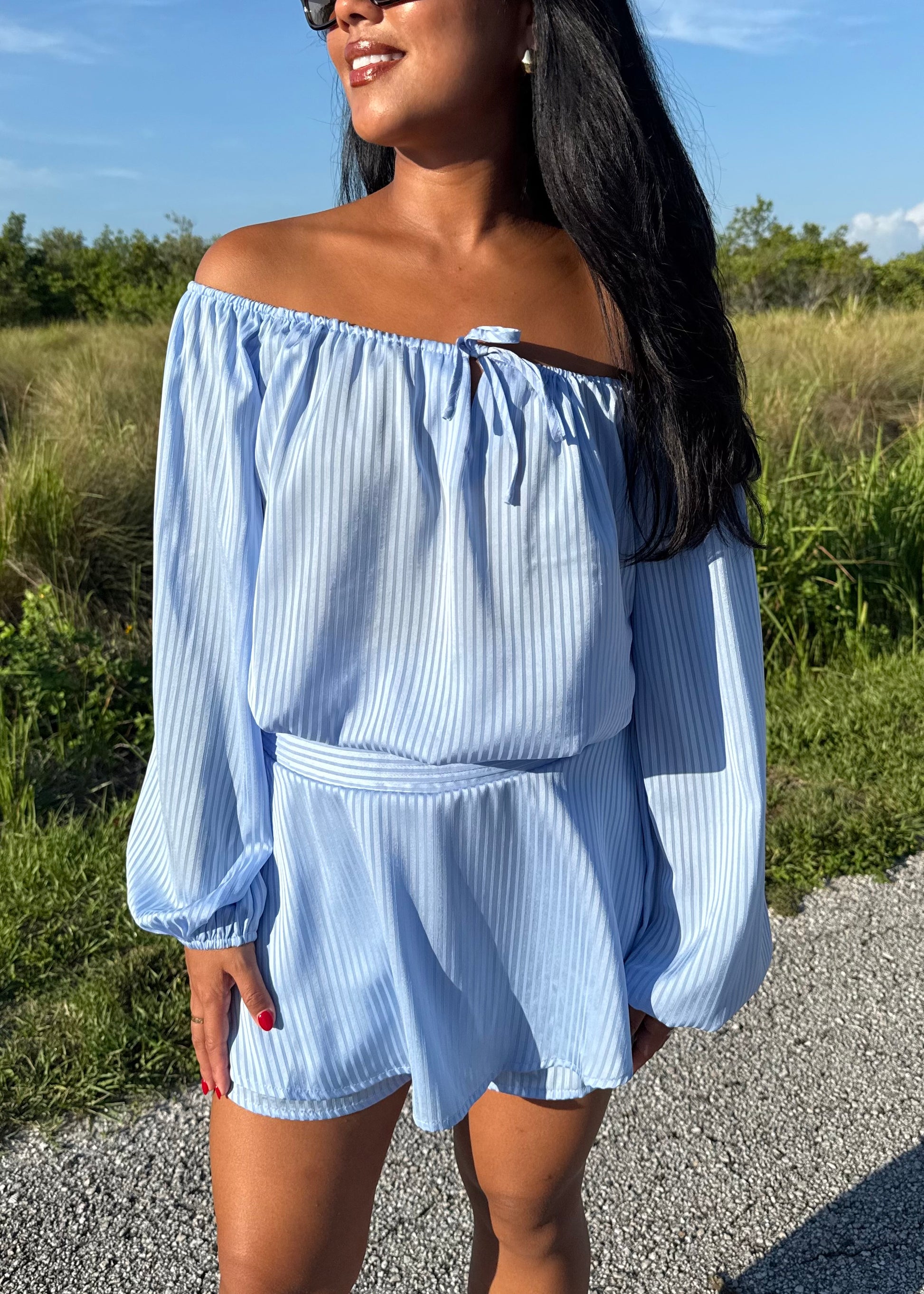 Girl wearing a blue off the shoulder long sleeve romper on a grass background