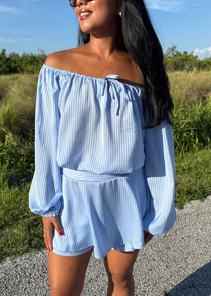 Girl wearing a blue off the shoulder long sleeve romper on a grass background
