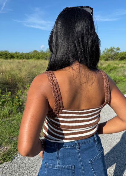 woman wearing a brown and white striped tank and jean shorts on a grass background