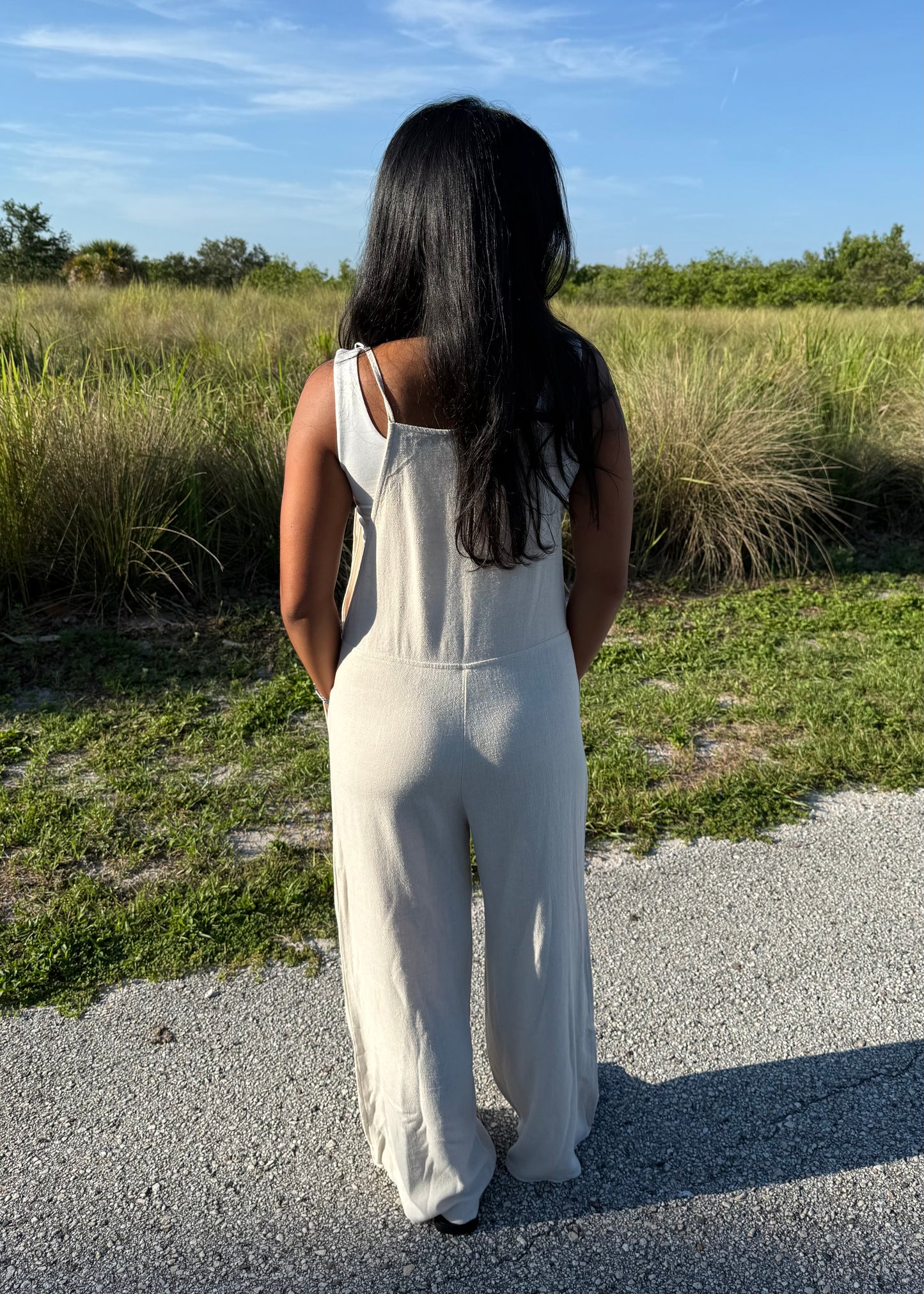 woman wearing a natural colored linen jumpsuit on a grass background