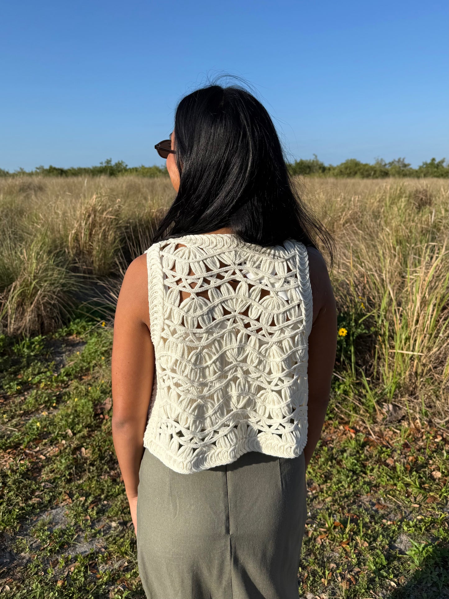 Person wearing a white crochet top in a natural setting