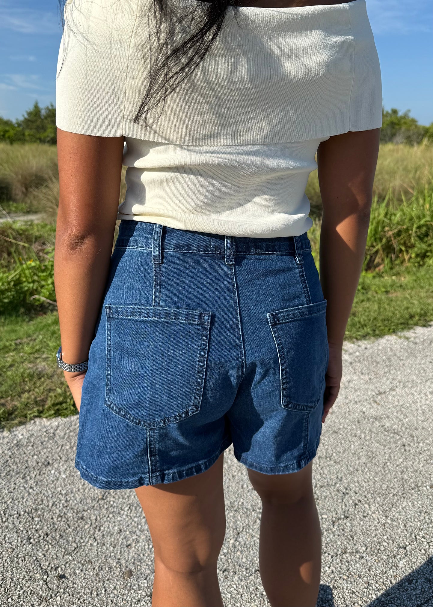 woman wearing denim shorts and a white top on a grass background