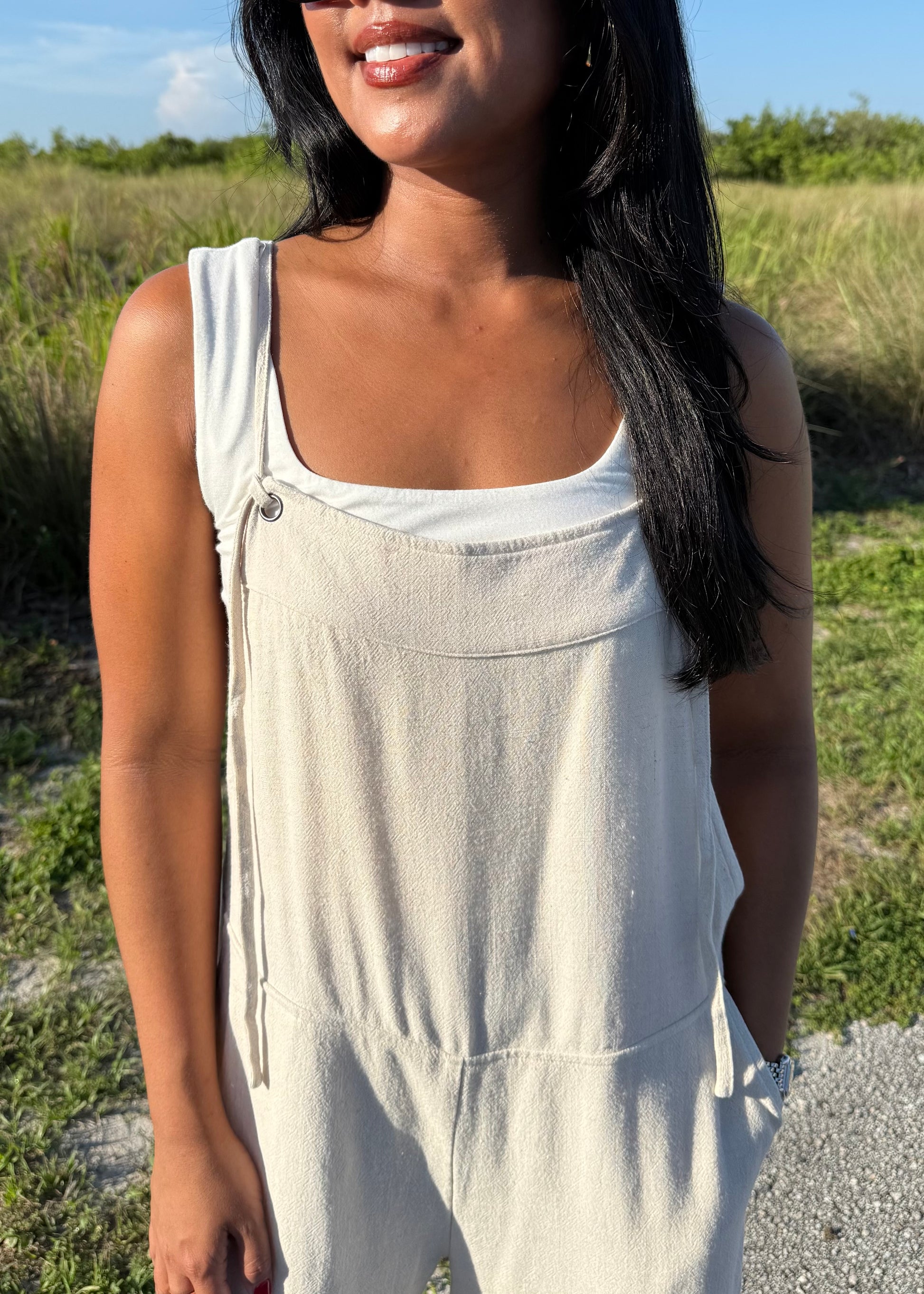 woman wearing a natural colored linen jumpsuit on a grass background