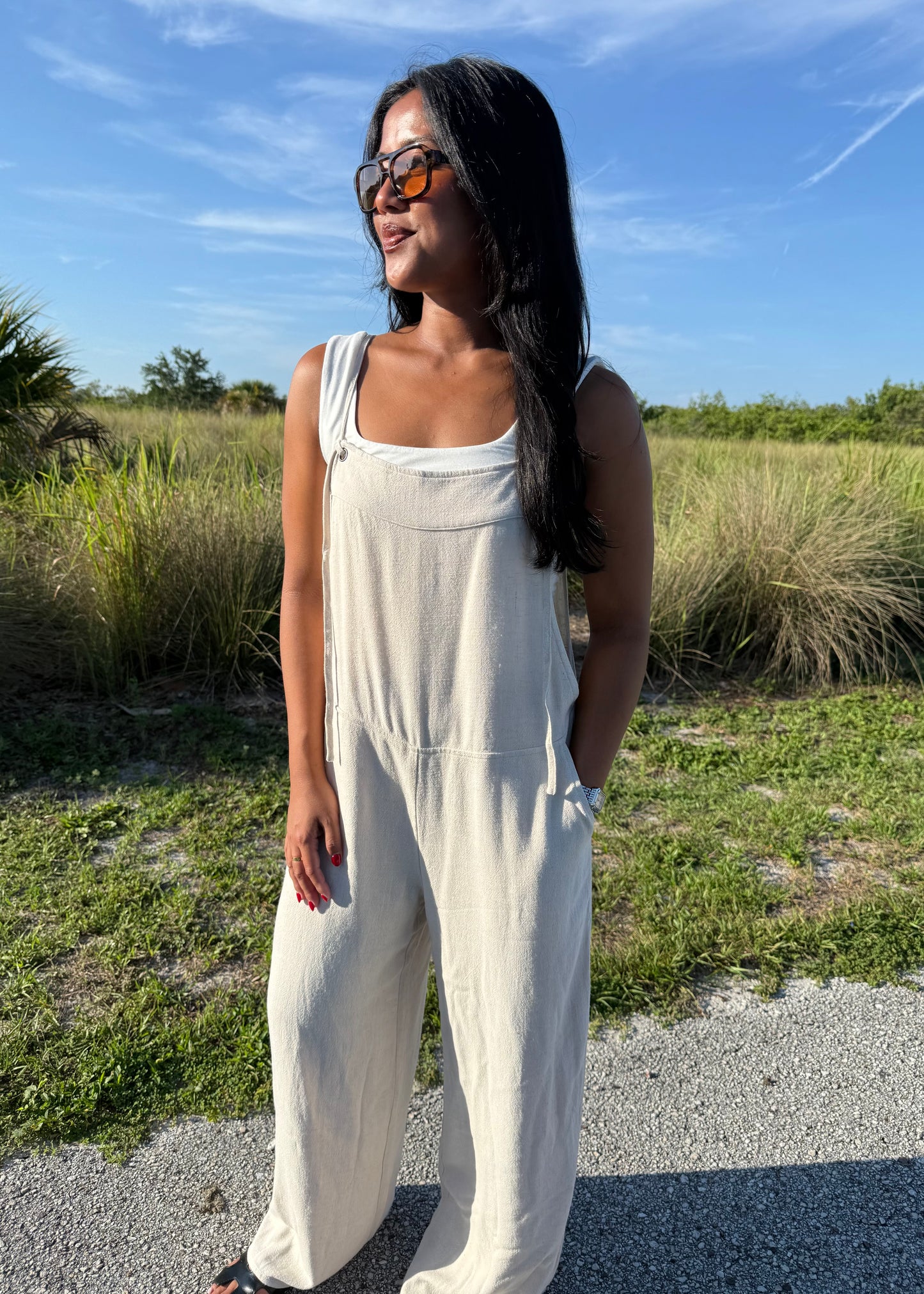woman wearing a natural colored linen jumpsuit on a grass background
