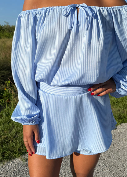 Girl wearing a blue off the shoulder long sleeve romper on a grass background