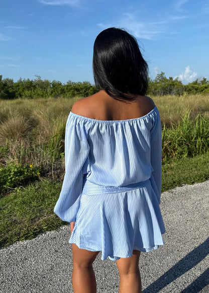 Girl wearing a blue off the shoulder long sleeve romper on a grass background