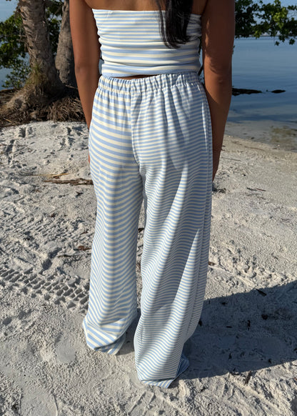 woman wearing striped top and striped pants on sand and water background