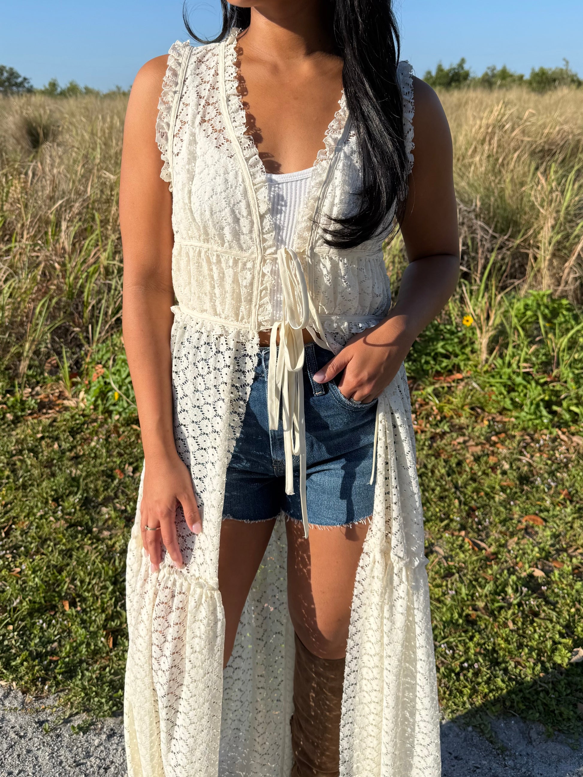 Woman wearing a long white lace cover-up in a natural setting