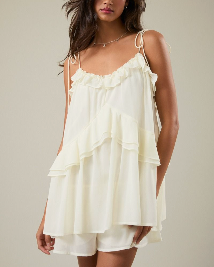 Woman wearing a white dress with ruffled layers on a neutral background
