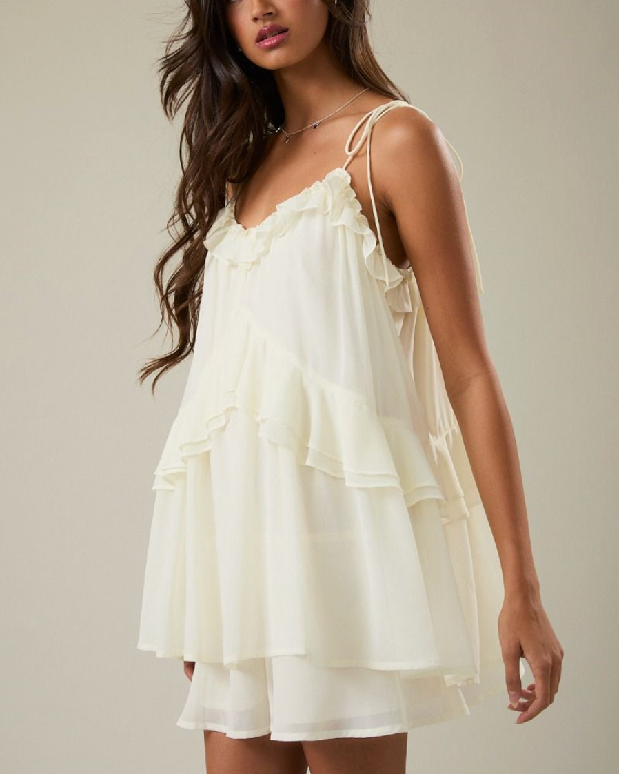 Woman wearing a white dress with ruffled layers on a plain background