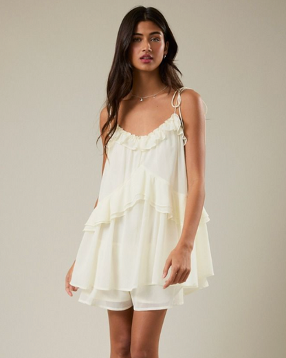 Woman wearing a white dress with ruffled layers on a plain background