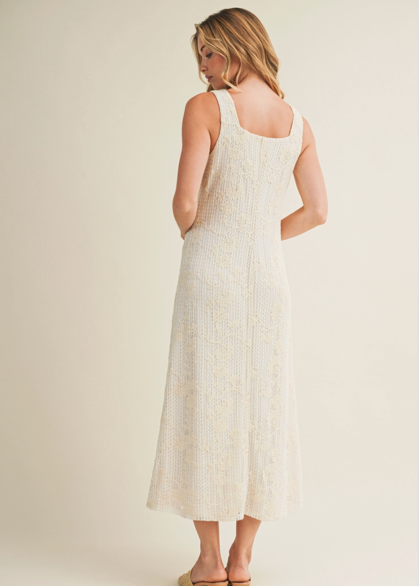 Woman wearing a white dress with a subtle pattern on a plain background