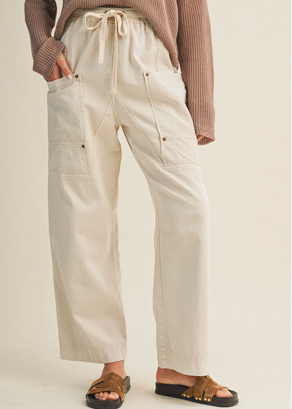 Person wearing beige pants with a plain background
