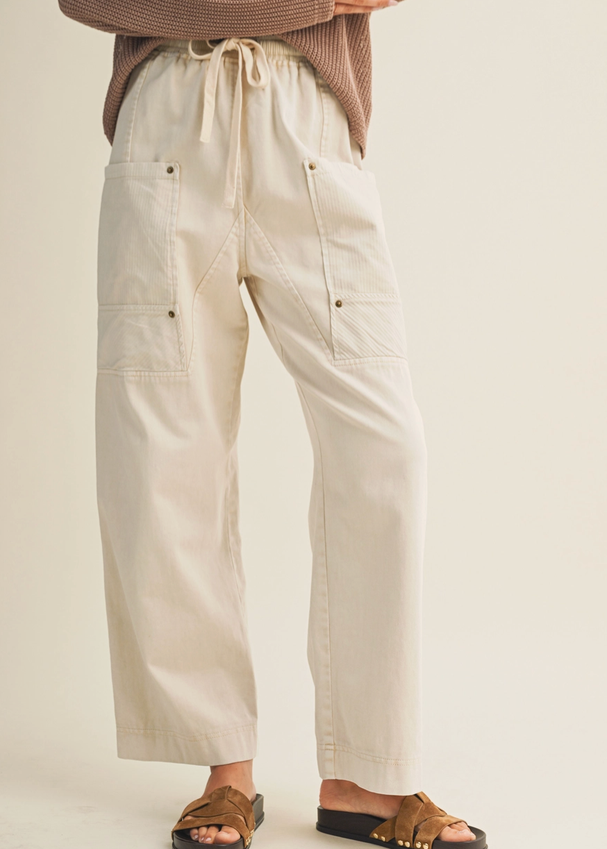 Person wearing beige pants and brown sandals on a plain background