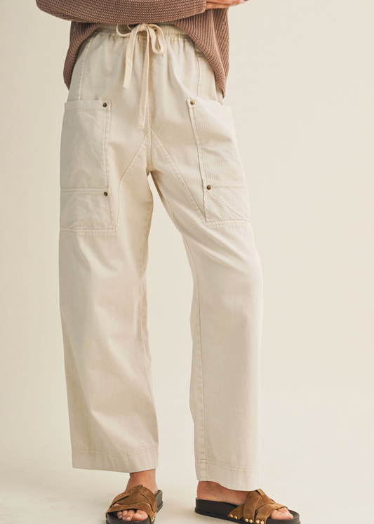 Person wearing beige pants and brown sandals on a plain background