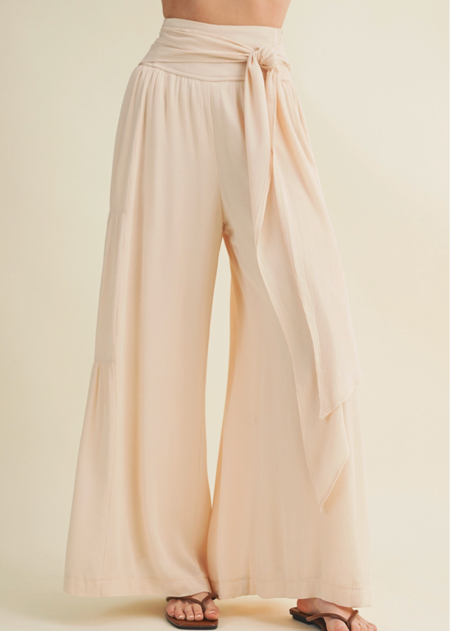 Beige wide-leg pants with a tie waist on a plain background