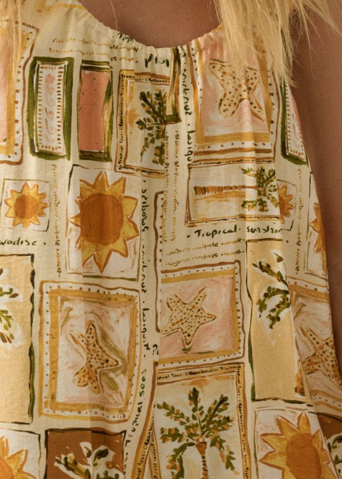 Close-up of a patterned romper with sun and starfish designs on a beige background