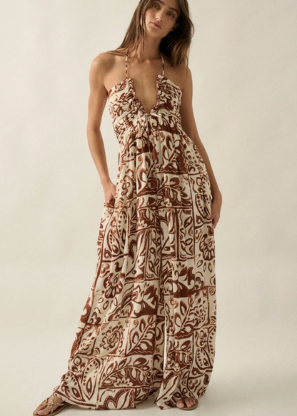 Woman wearing a patterned jumpsuit against a plain background