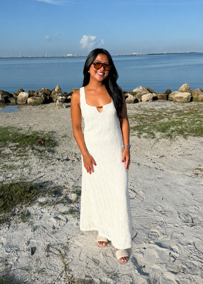 woman wearing a white dress on a beach with the water in background
