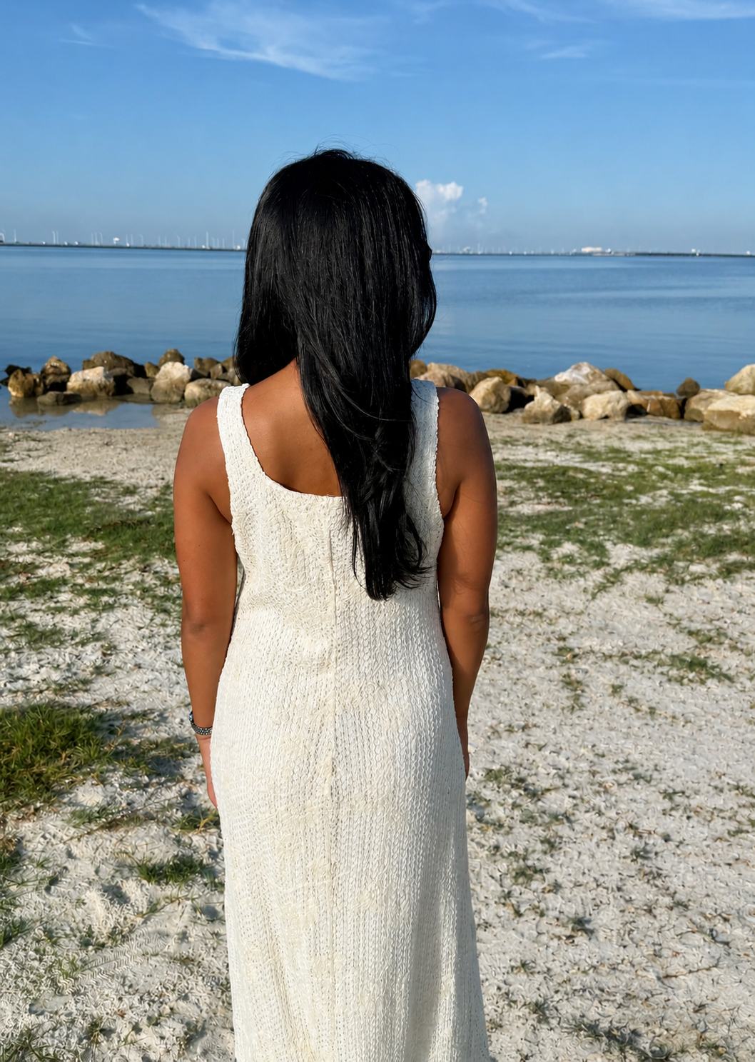 woman wearing a white dress on a beach with the water in background
