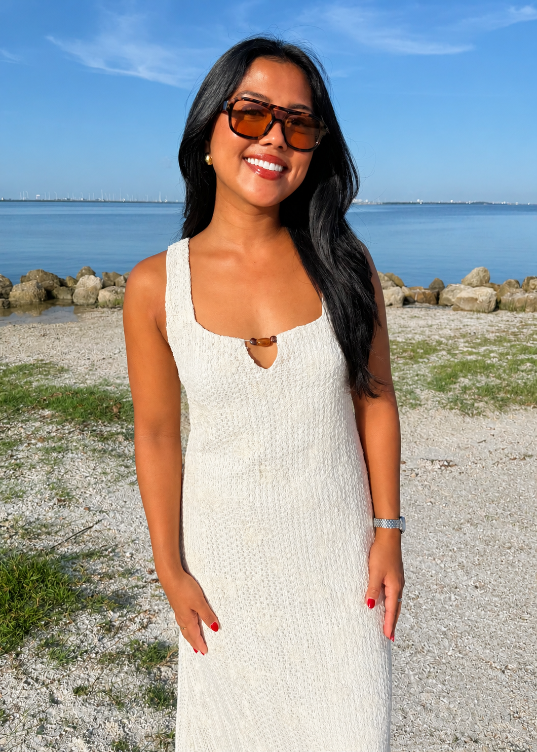 woman wearing a white dress on a beach with the water in background