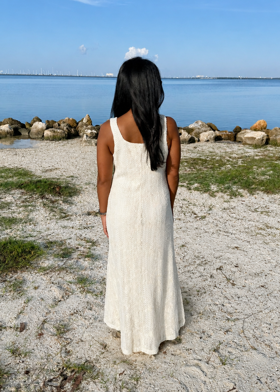 woman wearing a white dress on a beach with the water in background